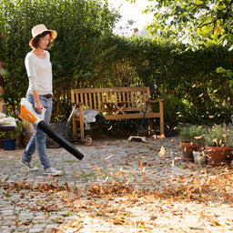 Hand held battery blower clearing leaves